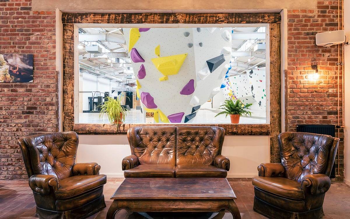 Gemütliches Bistro im Stuntwerk Krefeld mit Ledersesseln und Blick auf die Boulderhalle – ideal für eine Pause nach dem Training.