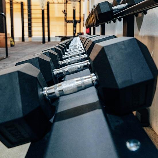 eihe schwarzer Hex-Kurzhanteln auf silbernem Hantelständer im Fitnessbereich des Stuntwerks. Klare Linien und Tiefenunschärfe betonen das hochwertige Equipment.