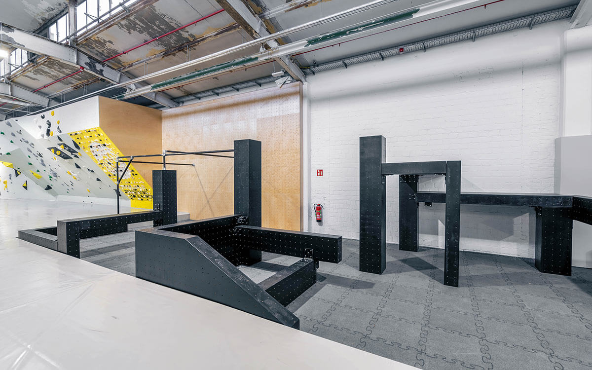Parkour-Setup im Stuntwerk Krefeld mit schwarzen Hindernissen und Boulderwänden im Hintergrund.