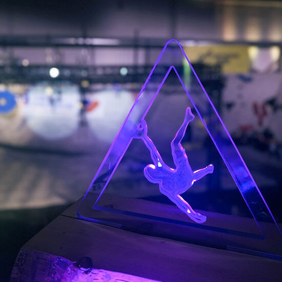 Leuchtender Pokal mit Stuntmoves Logo in Form eines kletternden Menschen – Symbol für Leistung und Leidenschaft im Bouldersport.