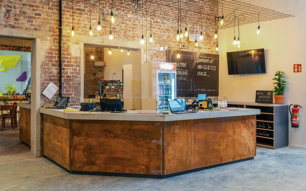 Freundlicher Empfangsbereich im Stuntwerk Krefeld mit industriellem Tresen und Café-Atmosphäre.