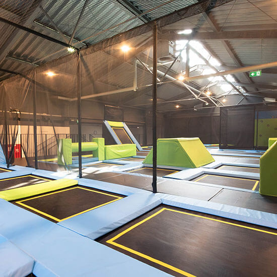 Weitläufiger Trampolinbereich mit verbundenen Sprungflächen, Schrägtrampolinen und gepolsterten Plattformen für Parkour- und Sprungtraining.
