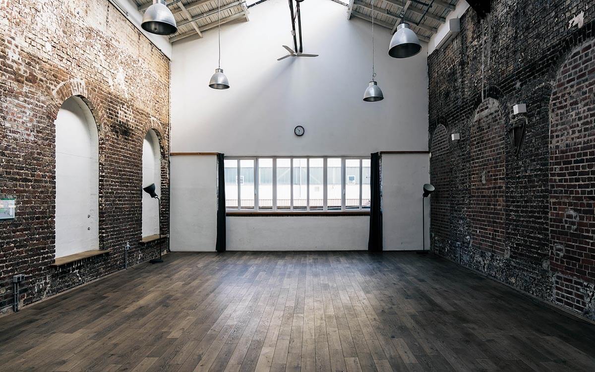 Großer heller Yogaraum mit Ziegelwänden und schönem Holzfußboden